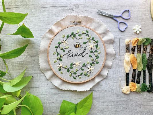 Bee embroidery hoop kit next to embroidery floss and craft scissors