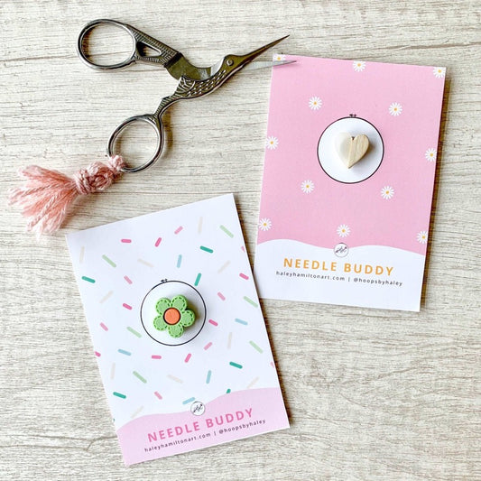 Heart needle minders next to bird embroidery scissors