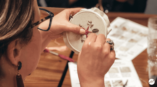 Girl embroidering a rose in an embroidery hoop 