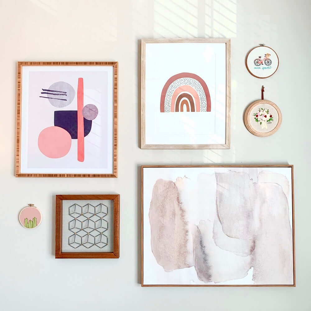 A gallery wall of framed art and embroidery hoop art