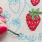 Hand embroidering a strawberry embroidery pattern onto fabric