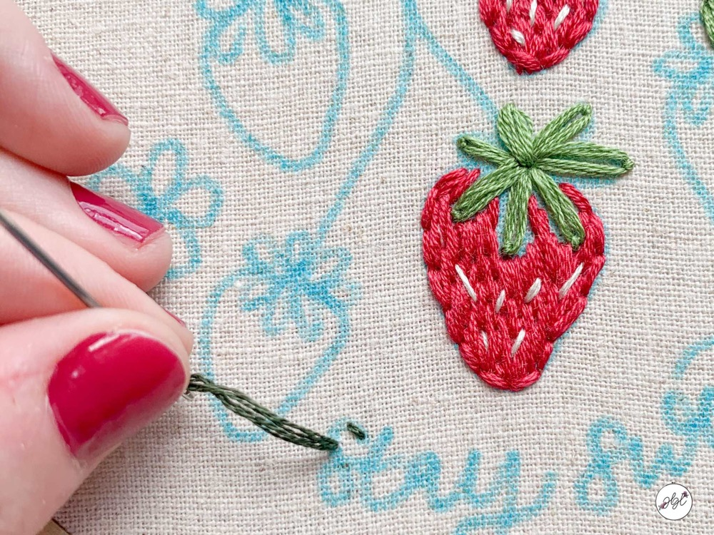 Hand embroidering a strawberry embroidery pattern onto fabric