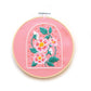 Embroidered flowers on pink fabric in an embroidery hoop
