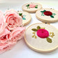 Rose embroidery hoops in four colors displayed next to pink roses