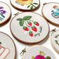Strawberry Embroidery hoop art displayed next to various embroidery designs